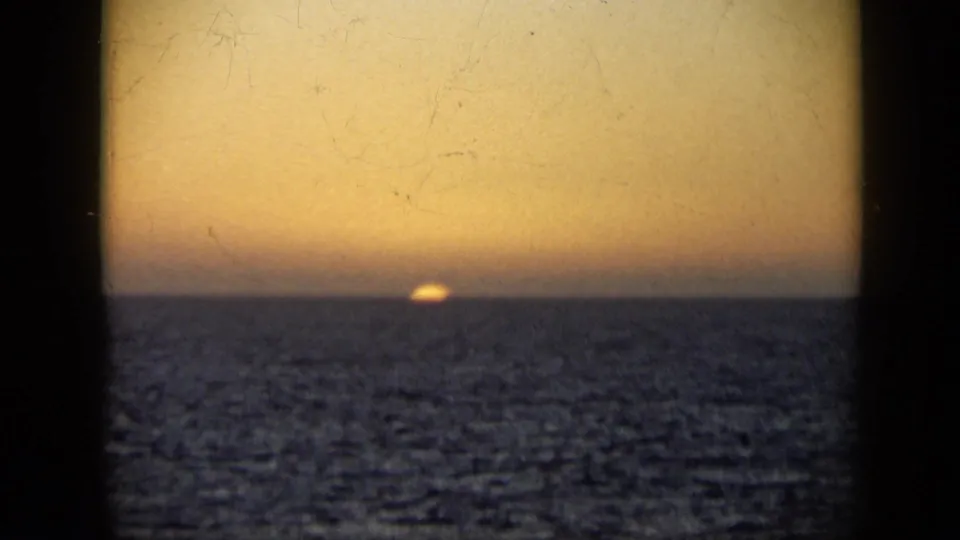 1959 Venezuela 8mm frame showing a golden sunset over open water, viewed through dark vertical framing from a boat.