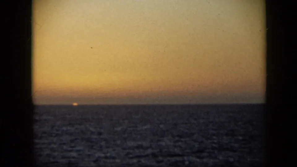 Late-1950s 8mm travel footage shows the sun nearly gone at the horizon over a dark, textured tropical sea.