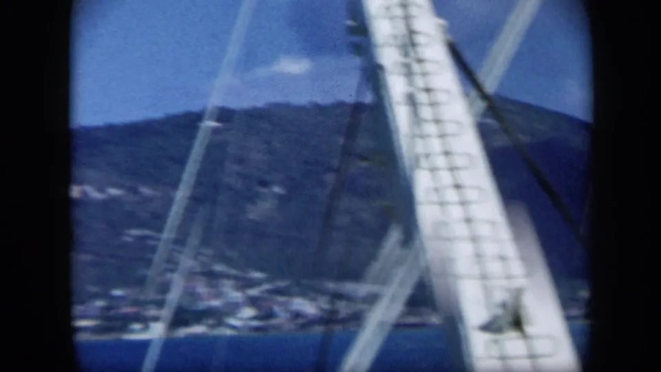 1959 Venezuela 8mm frame with boat rigging in front of a distant coastal hillside and blue water.