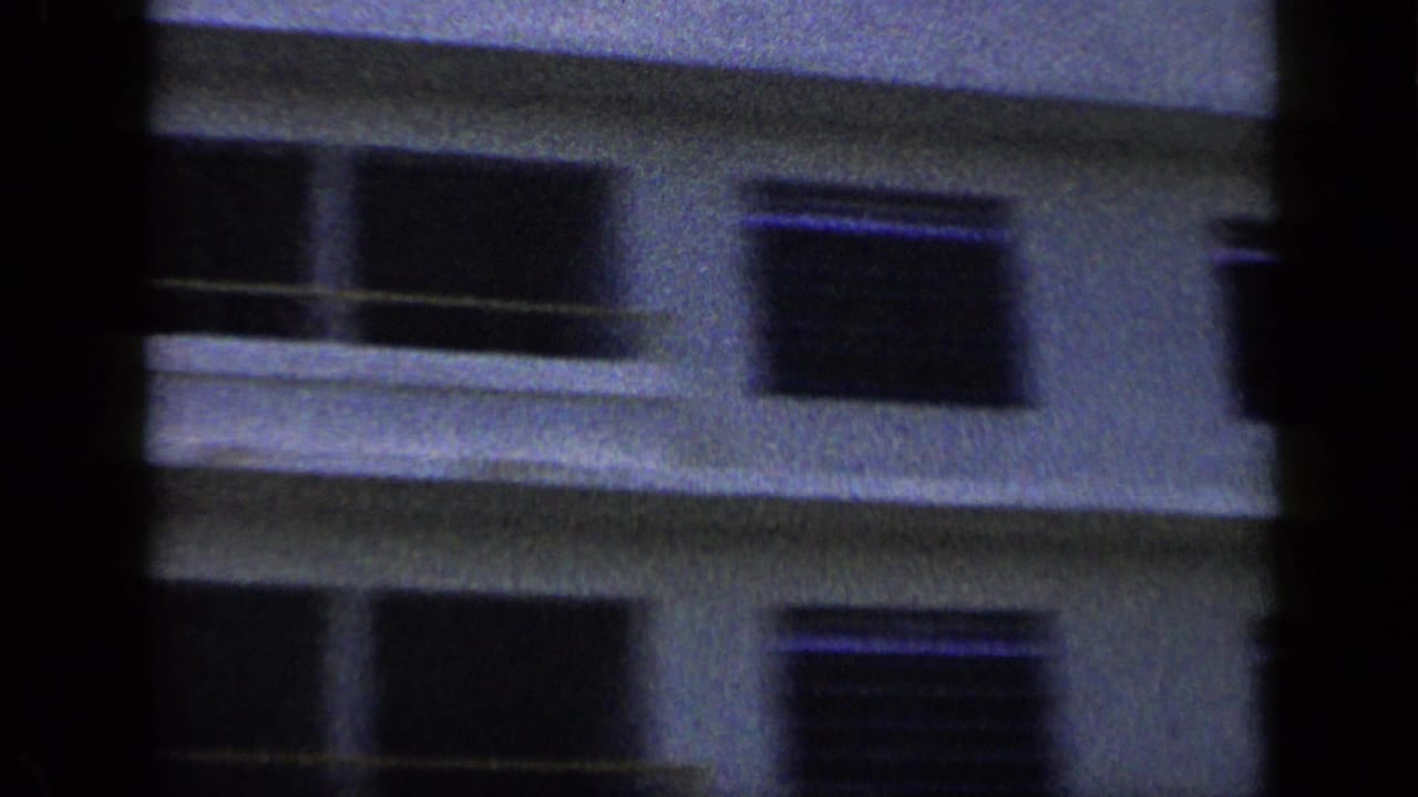 Soft-focus hotel facade with balconies and dark window openings.