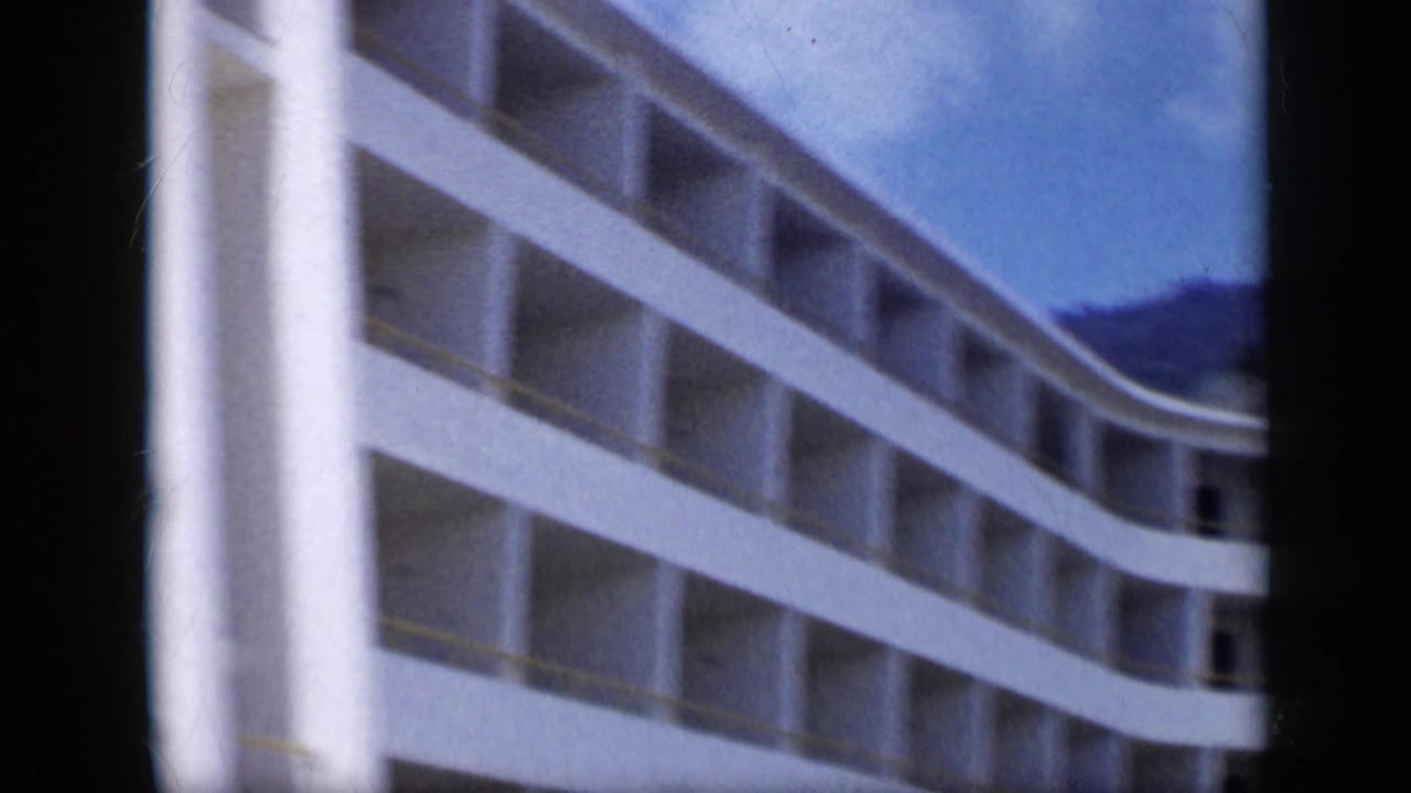Close 8mm view of a curved white modern building facade in Venezuela, with repeated balcony openings and soft motion blur.