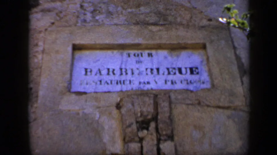 A weathered stone wall holds a readable sign, TOUR DE BARBE BLEUE, in this 1959 Venezuela travel-home-movie frame.