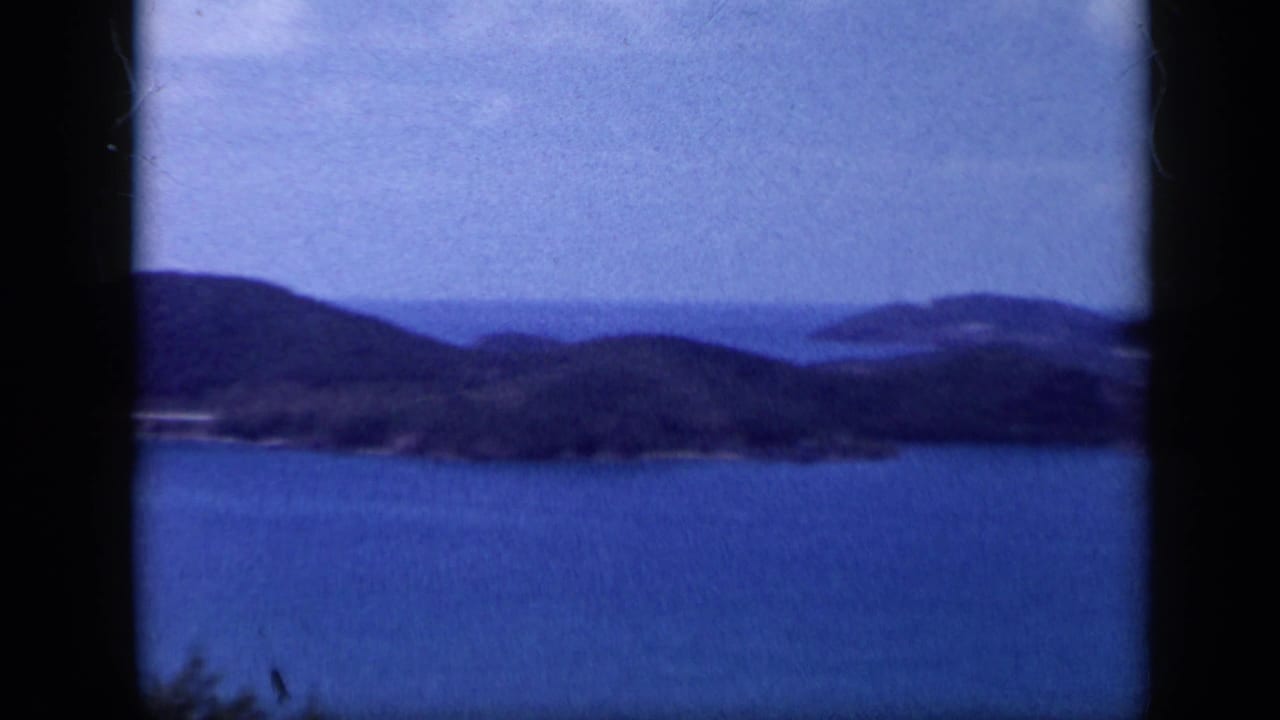 Wide bay with wooded hills and distant shoreline under a blue sky.