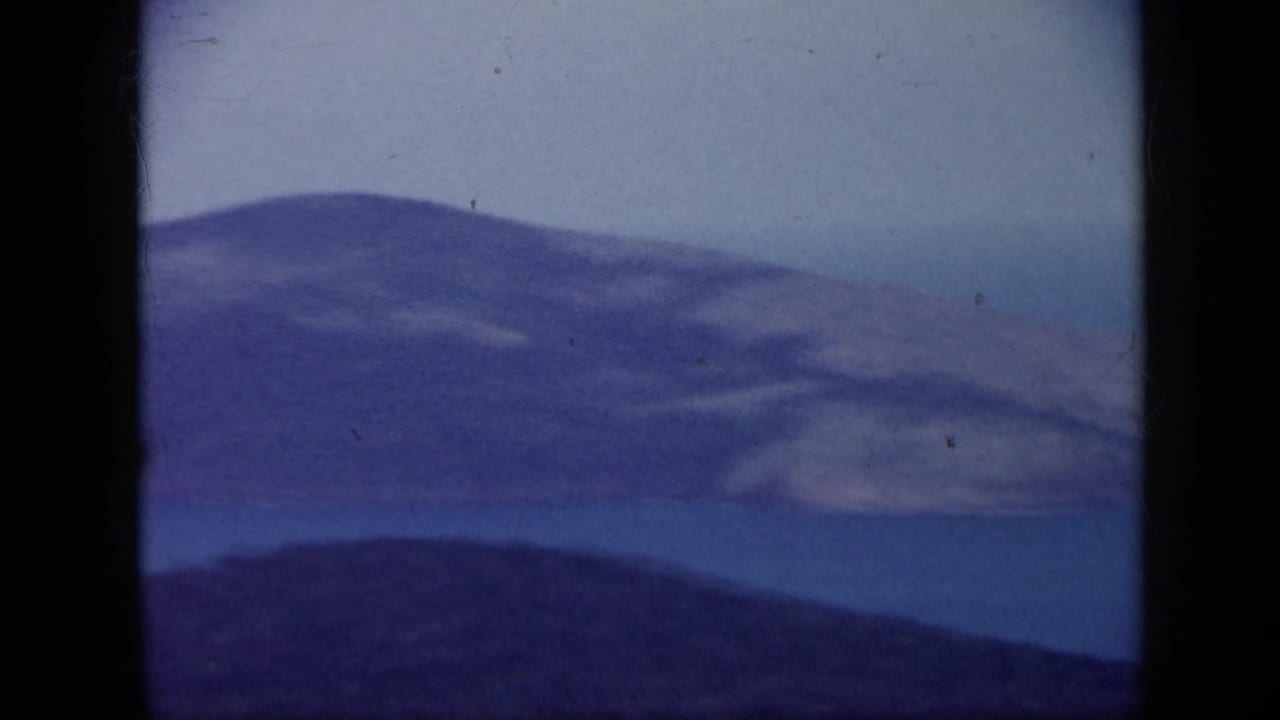 1959 Venezuela home-movie frame showing hazy hills and blue coastal water through a dark window-like border.