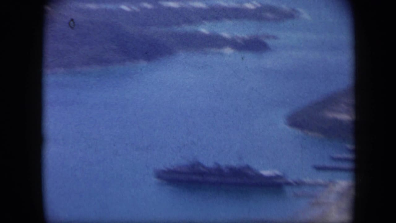 1959 Venezuela 8mm aerial frame with a large ship near shore, blue water, and partial island coastline.