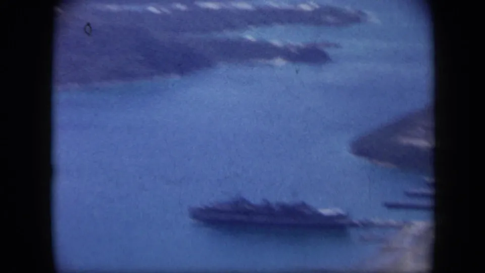 1959 Venezuela 8mm aerial frame with a large ship near shore, blue water, and partial island coastline.