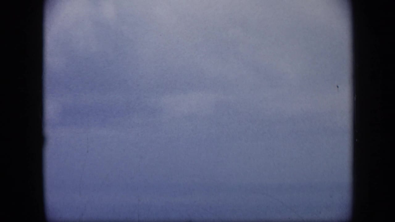 Soft, blurred 8mm frame from the Venezuela aerial sequence, showing pale sky or water during a quick camera shift.