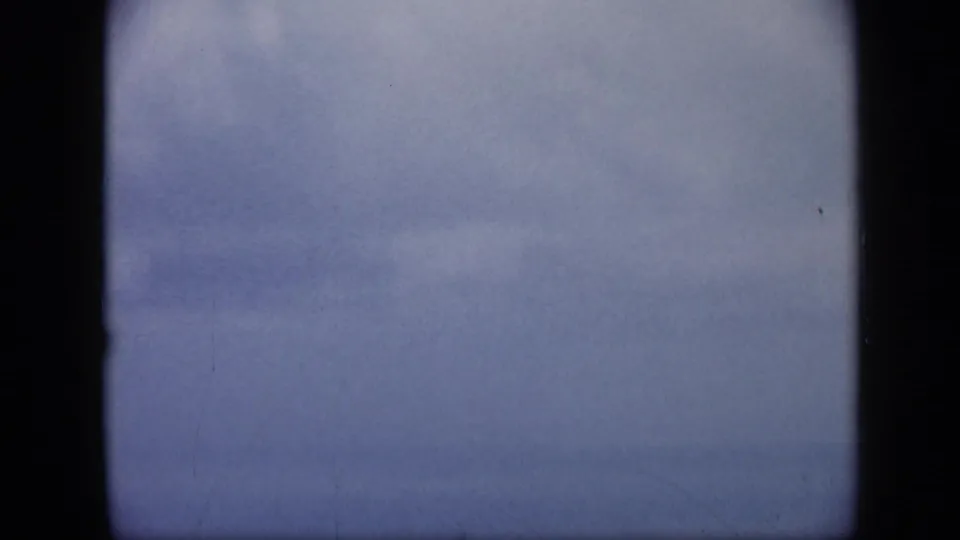 Soft, blurred 8mm frame from the Venezuela aerial sequence, showing pale sky or water during a quick camera shift.