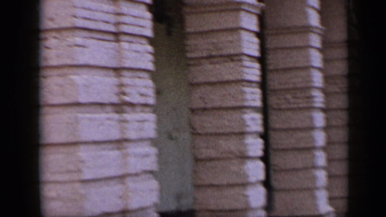 1959 Venezuela street footage showing textured stone columns and the edge of a hanging commercial sign.
