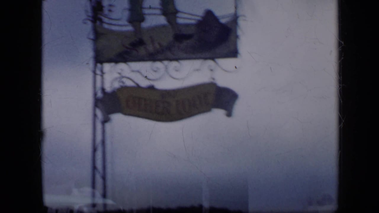 Soft 8mm frame of the hanging Continental sign structure and a lower commercial sign against a pale sky in Venezuela.