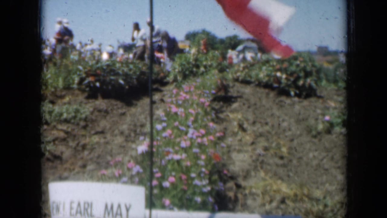 1961 Missouri 8mm frame showing a red and white flag above planted flower rows with visitors beyond.