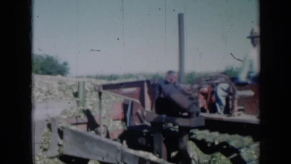 1961 Missouri 8mm frame showing a person operating or riding a red bulldozer as it works beside a pale mound in a rural field.