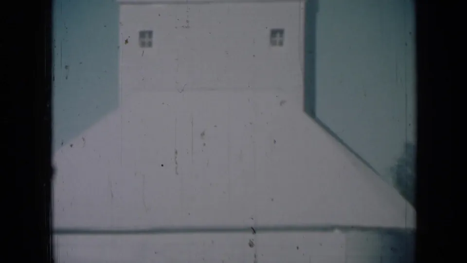 Large white farm storage building in 1961 Missouri footage, framed close with small upper windows visible.