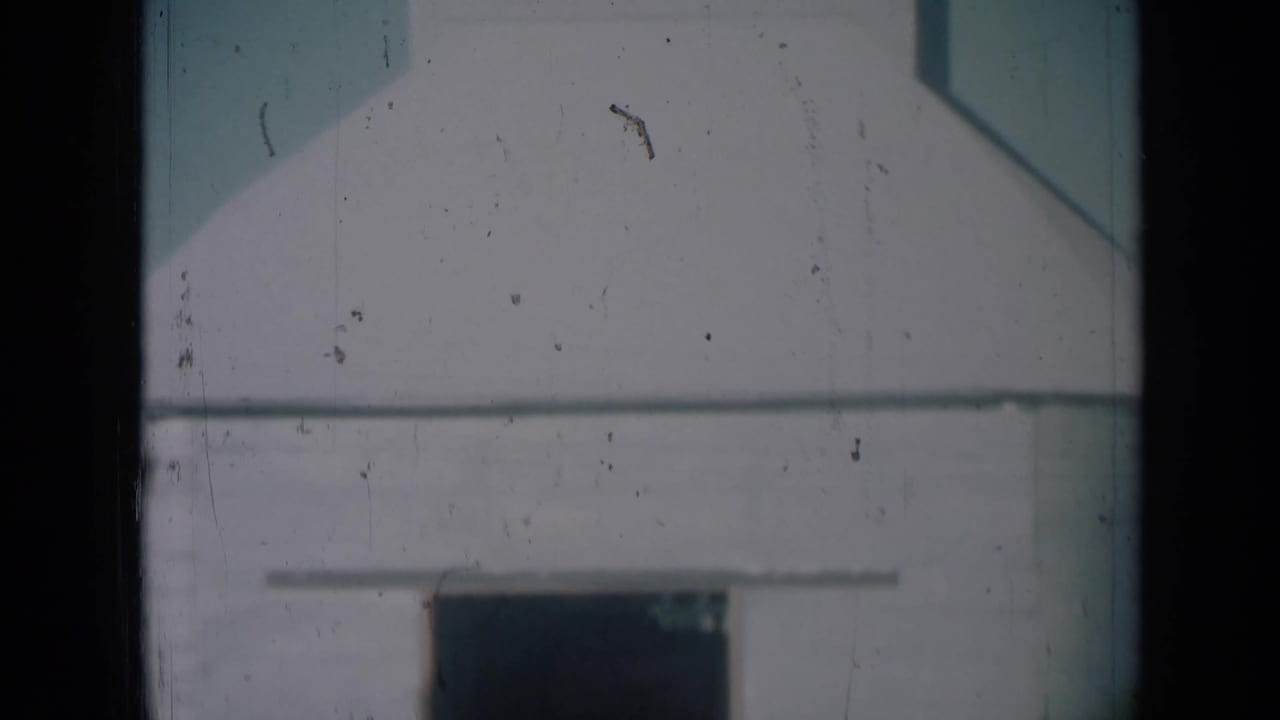 White agricultural storage building in Missouri, with a dark lower doorway and soft 8mm film grain.