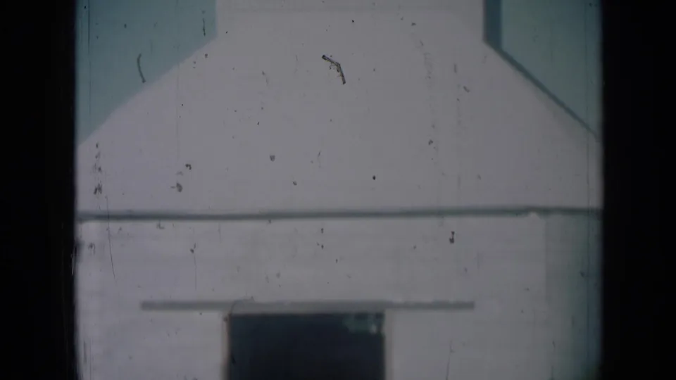 White agricultural storage building in Missouri, with a dark lower doorway and soft 8mm film grain.