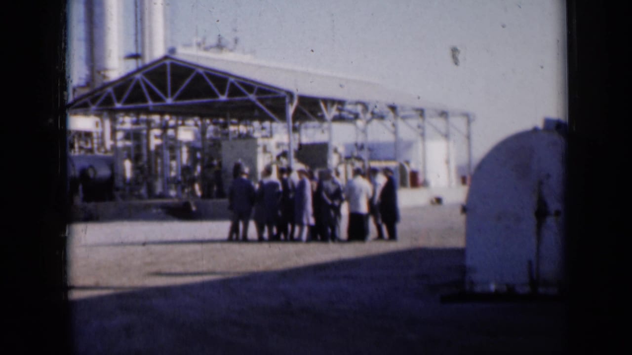 Group of people gathered outside a metal structure with tanks nearby.