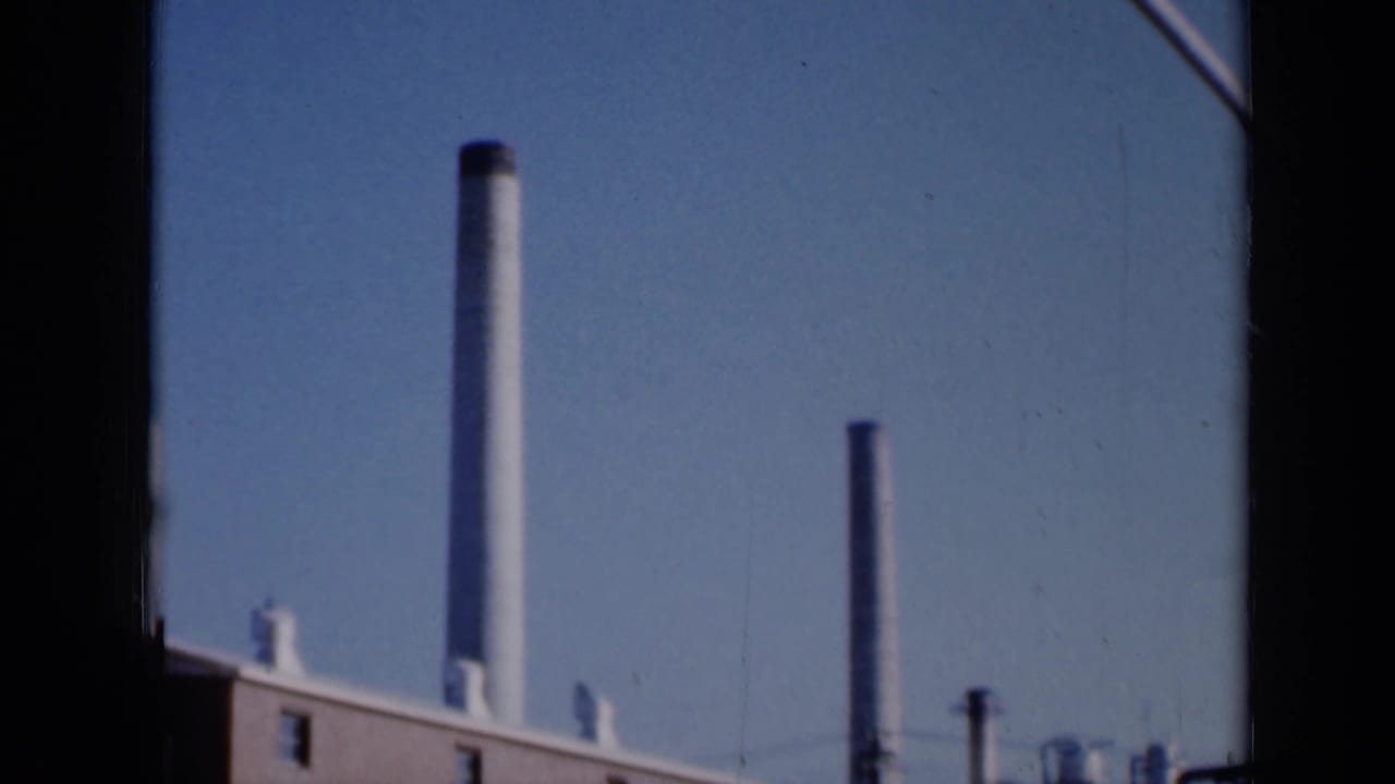 Brick industrial building with tall smokestacks against a blue sky.