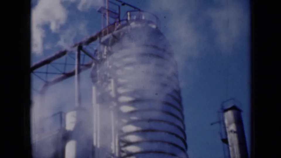 1961 Missouri industrial frame showing a tall vent or stack structure emitting white smoke or steam beside metal framework.