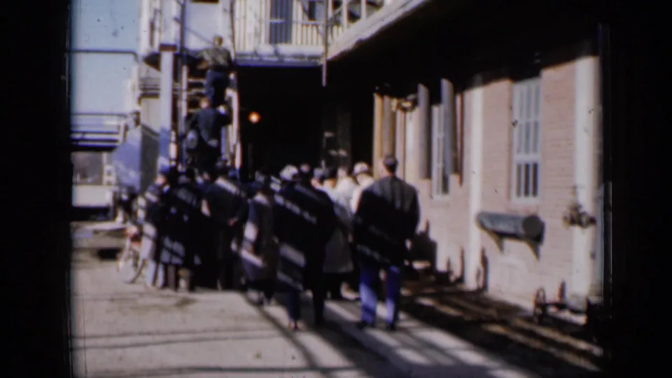 The 1961 Missouri exterior view shows men gathered tightly near metal stairs, with a bicycle and brick wall visible nearby.