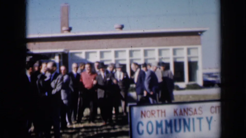 Men gather outside a community building beside a visible North Kansas City Community sign in Missouri footage from 1961.