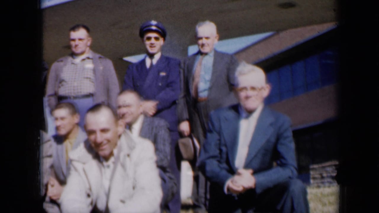 Men of different ages pose outside a Kansas City-area building, with one uniformed man standing near the back.