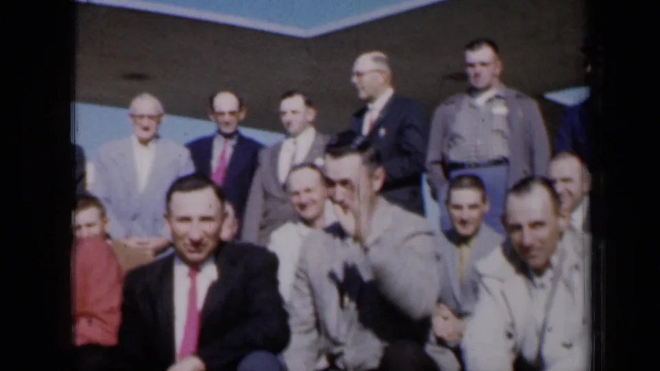 Group of men pose outdoors in 1961 Missouri, seated and standing in front of a building entrance area.