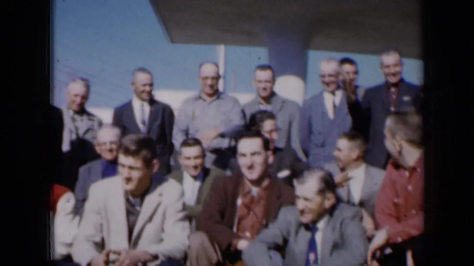 The 1961 Missouri group portrait loosens into a candid moment as men laugh and look around outdoors.