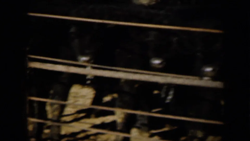 The closing frame is dark and underexposed, showing horizontal rails or structural lines with indistinct figures or objects below.