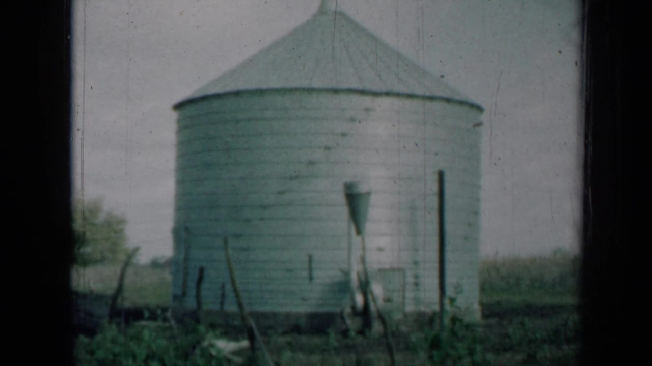 A white metal silo on a rural Missouri farm appears in faded 1961 8mm footage.