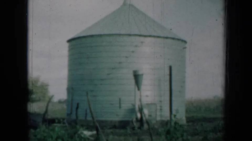 A white metal silo on a rural Missouri farm appears in faded 1961 8mm footage.