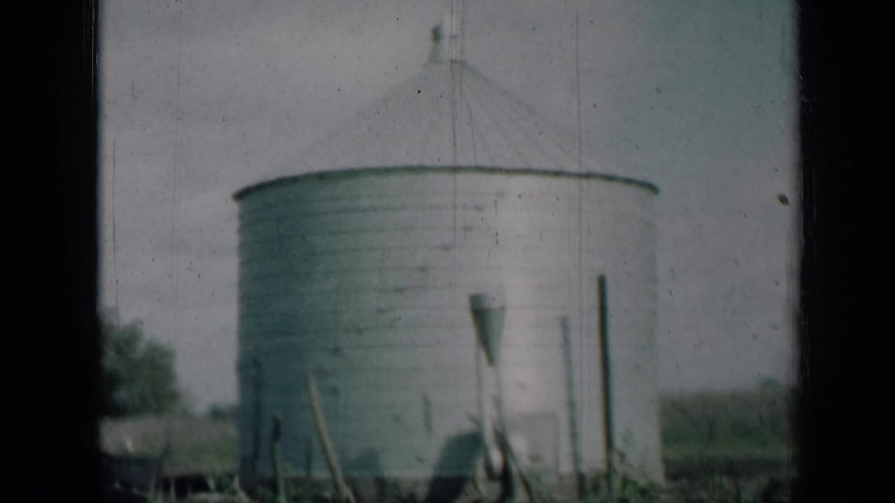 1961 Missouri 8mm frame showing a round aluminum farm silo with a conical roof, grass, posts, and dark film borders.