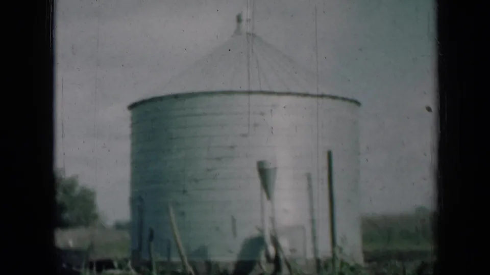1961 Missouri 8mm frame showing a round aluminum farm silo with a conical roof, grass, posts, and dark film borders.