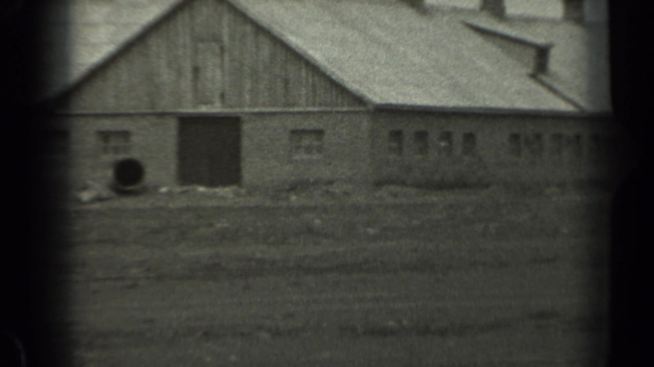 1961 Missouri 8mm frame showing a weathered barn, open field, rooflines, and dark film gate edges.