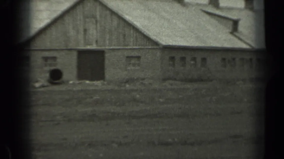 1961 Missouri 8mm frame showing a weathered barn, open field, rooflines, and dark film gate edges.