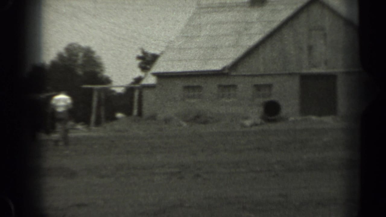 Barn and farmyard with a small distant figure near the buildings.