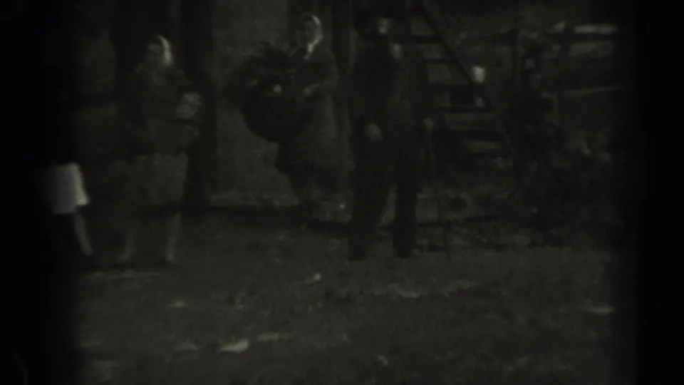 Adults gather near a wooden stair or platform in grainy 1961 Missouri 8mm footage.