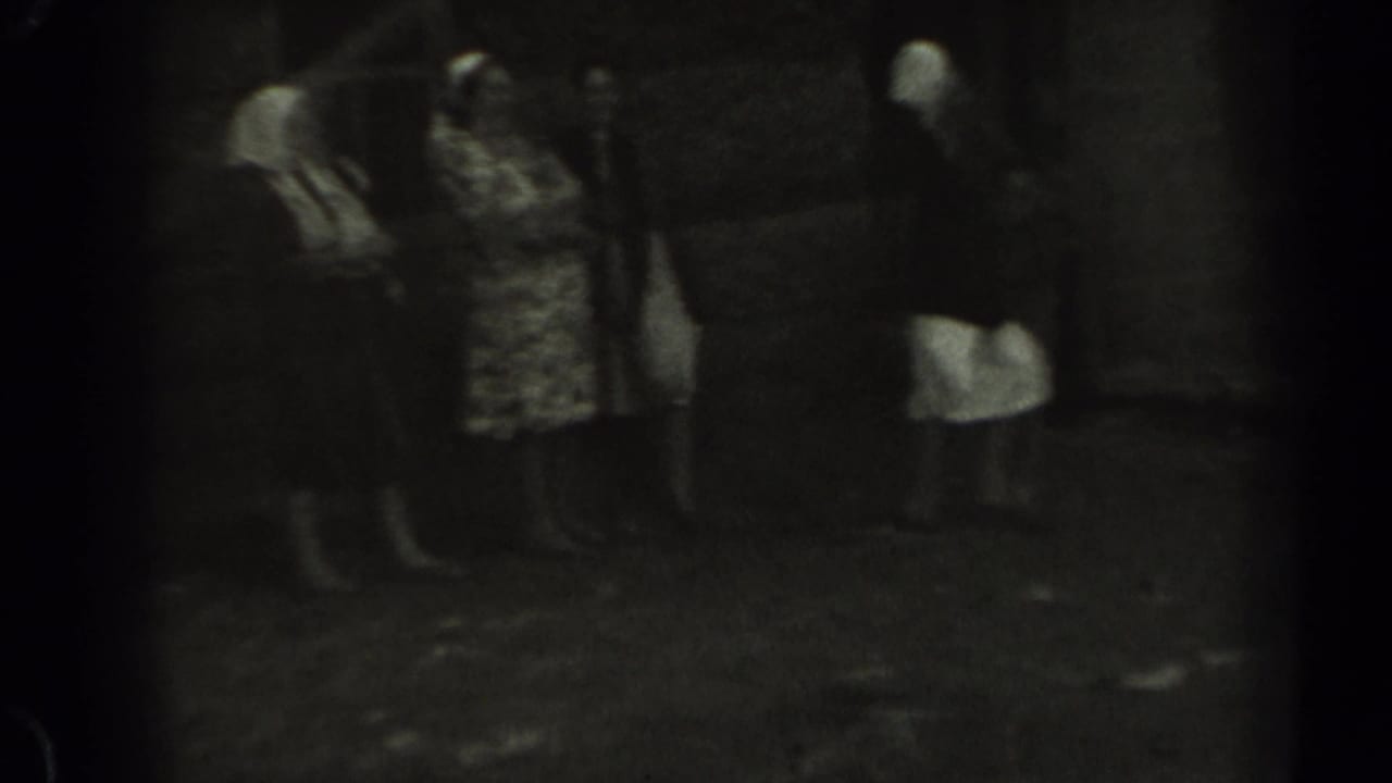 A small group of women stands together near a wooden structure in 1961 rural Missouri footage.