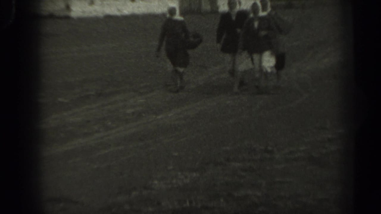 In 1961 Missouri home-movie footage, three older women in headscarves and skirts walk across a dirt field.
