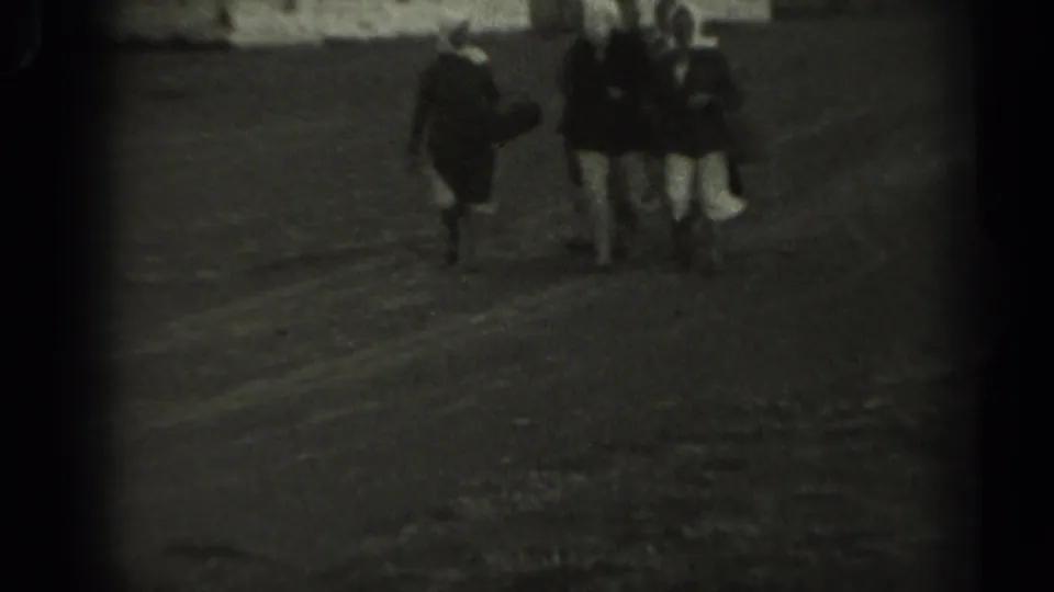 Three older women continue across the dirt field in soft, grainy 8mm footage from Missouri, 1961.