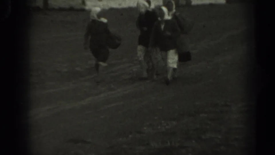 Three older women walk away across a rural dirt area, one holding a dark handbag, in grainy 1961 Missouri 8mm footage.