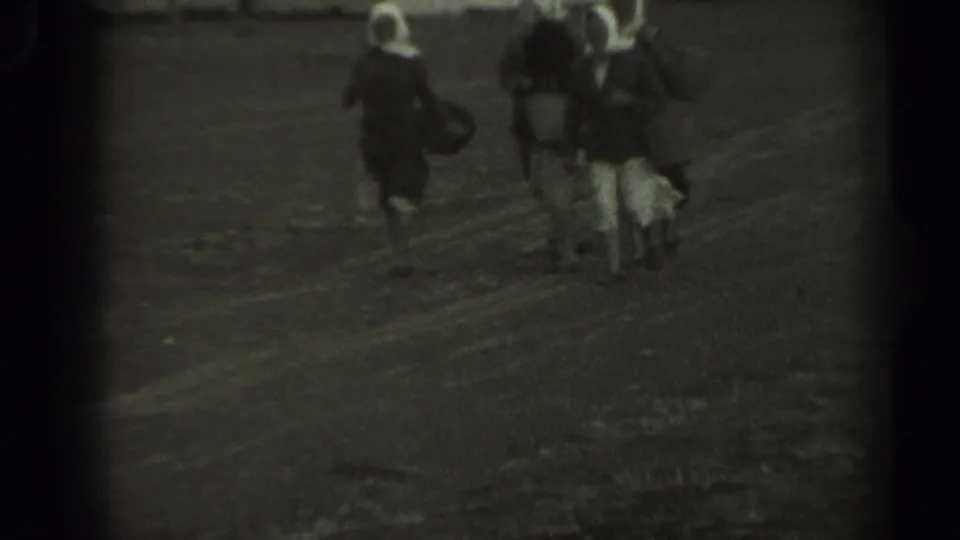 1961 Missouri 8mm frame showing three women in dark dresses and white head coverings walking together on an unpaved path.