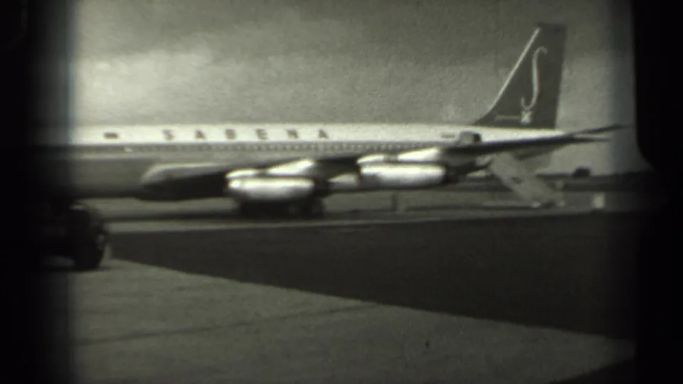 1961 Missouri 8mm frame showing a Sabena airliner side view on the tarmac, with tail marking, engines, and overcast sky visible.