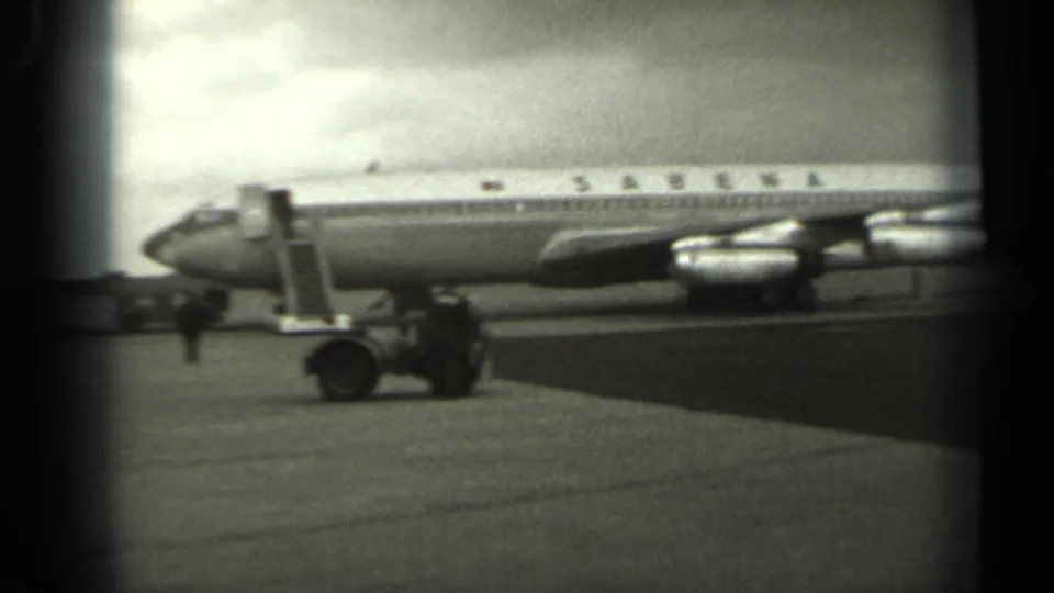 1961 Missouri 8mm frame showing the nose of a Sabena airliner, lowered access ladder, ground vehicle, and small ground-crew figure.
