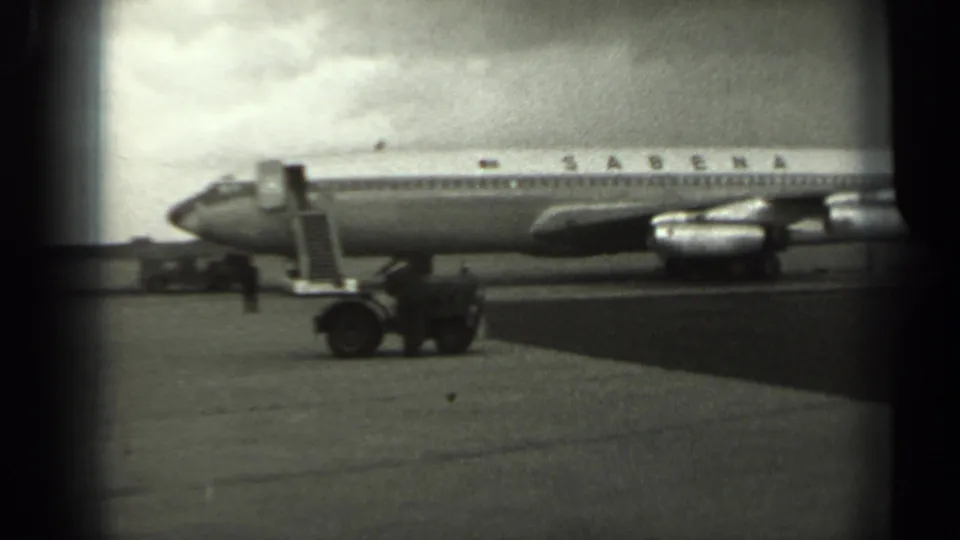 1961 Missouri 8mm frame showing a Sabena airliner parked on the tarmac, with ladder, ground vehicle, and small crew figure visible.