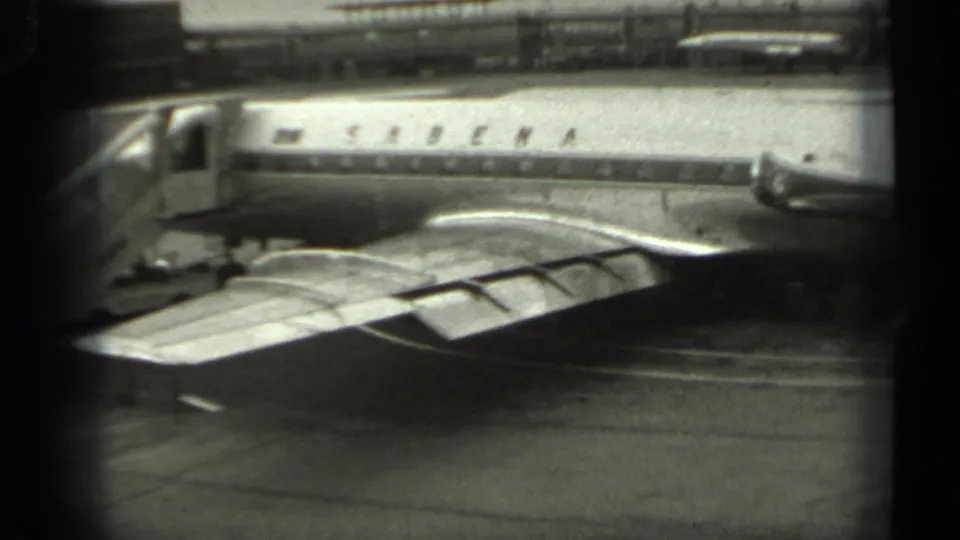 1961 Missouri airport footage shows a Sabena aircraft with boarding stairs, wing surfaces, and tarmac detail in a home-movie frame.