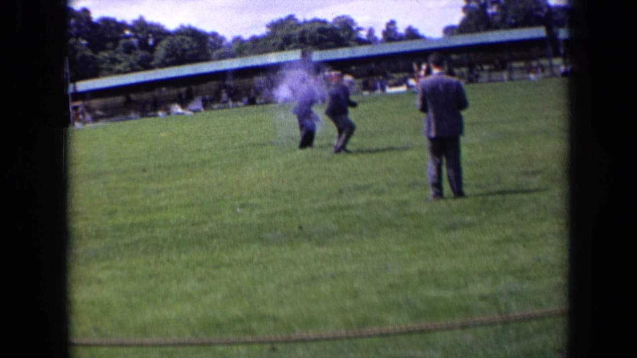 A man fires a starter gun as smoke rises on the lawn.