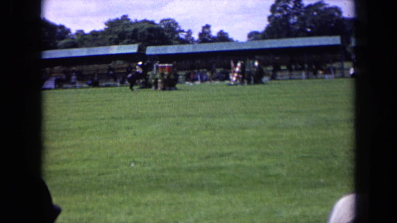 A horse and rider approach or pass the jump area during a 1963 England outdoor equestrian event, seen from a distant spectator position.