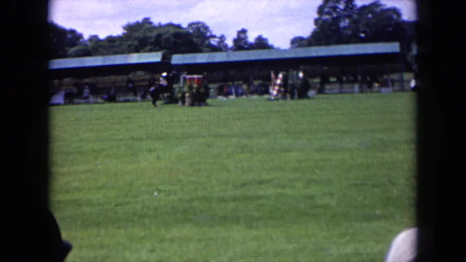 A horse and rider approach or pass the jump area during a 1963 England outdoor equestrian event, seen from a distant spectator position.