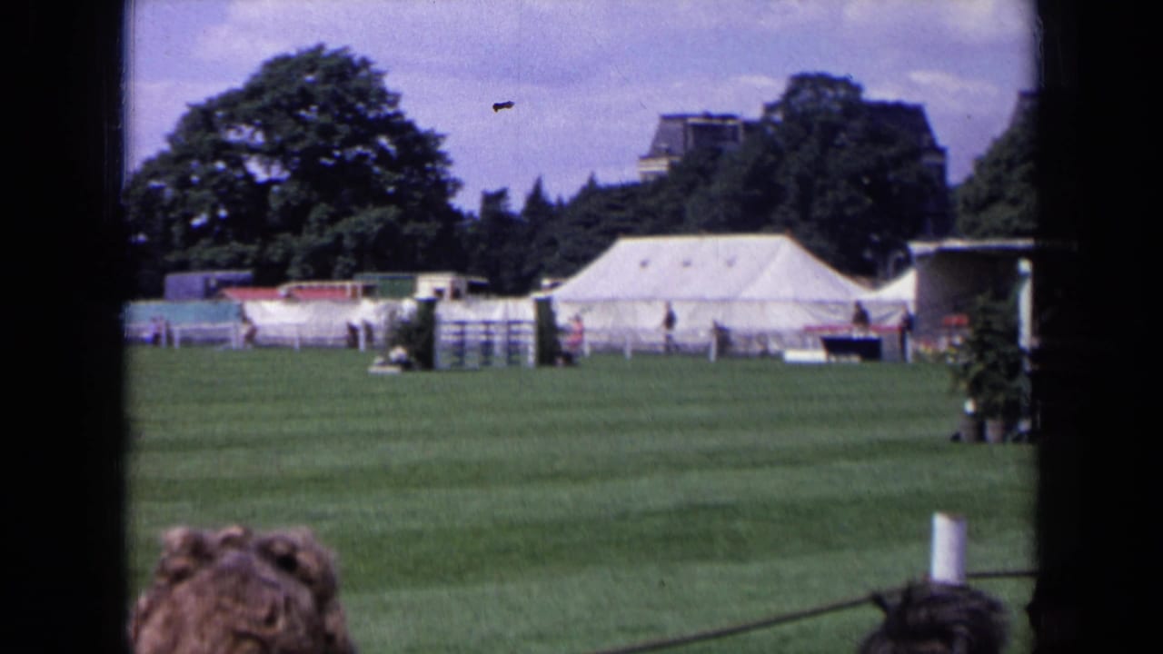 1963 England 8mm frame showing the equestrian field after the horse has moved out of view, with tents and spectators visible.