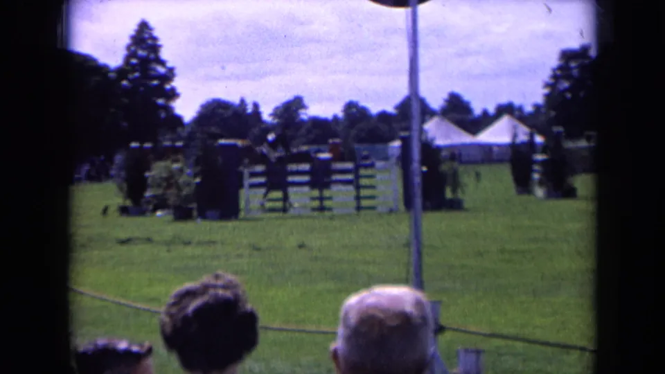 A wider 1963 England view shows show-jumping fences on a green field, with spectators' heads in the foreground and tents beyond.